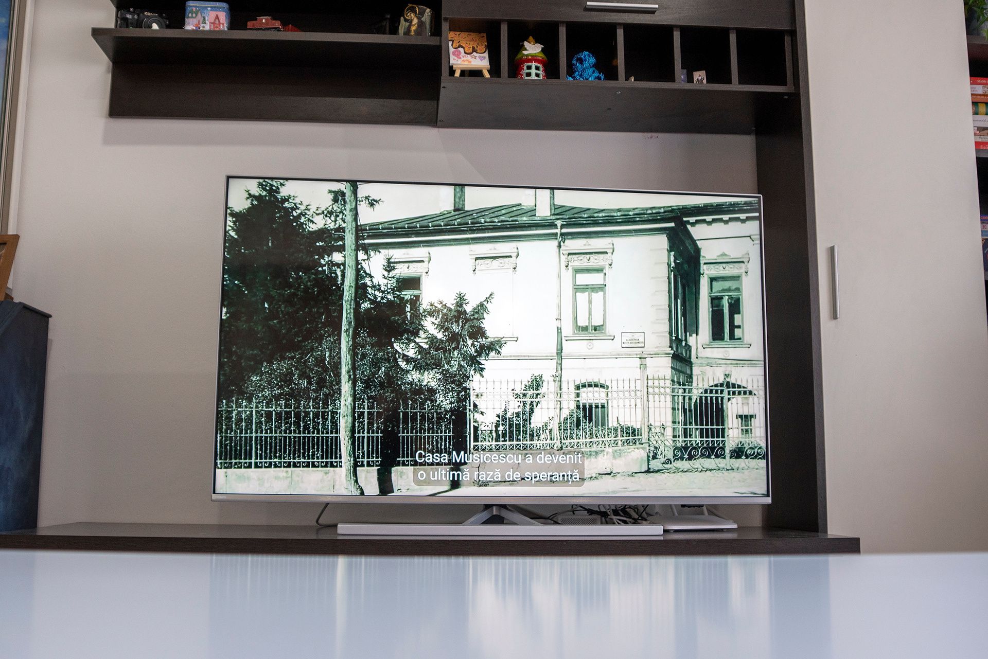 TV screen showing a black-and-white historical photo of Casa Musicescu with a Romanian caption